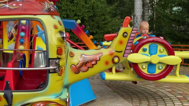 brave pilot toddler child in amusement park, attraction colorful airplanes will lift children Divo Ostrov, St. Petersburg, Russia
