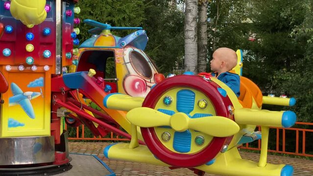 brave pilot toddler child in amusement park, attraction colorful airplanes will lift children Divo Ostrov, St. Petersburg, Russia