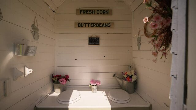 push in shot of the inside of a decorated and repurposed out house toilet room