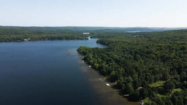 Beautiful sunny day illuminates green forest and lakeside docks to deep blue drop off in water