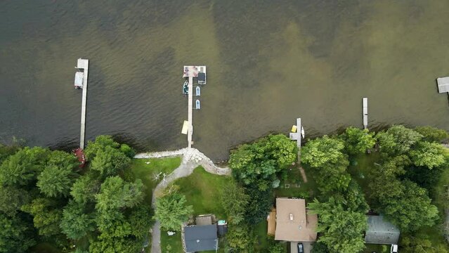 Top down bird's eye view, private docks with boats watercraft jetskis docked at lake house vacation spots