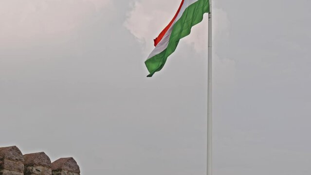 big indian flag swaying in the sky with clouds in the background tilt up shot daytime 4k 25p