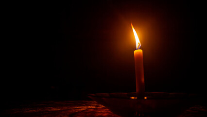 a burning candle against a dark background