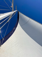 View of the sail and mast of sailing yacht against bright blue sky