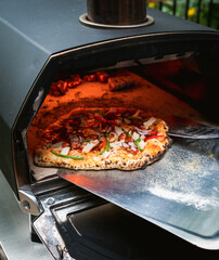 Close up of pizza being cooked outside in a portable pizza oven.