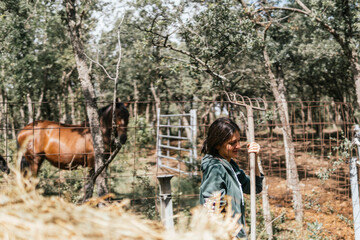 young farmer girl with a rake working on a horse farm