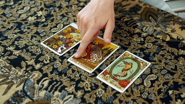 A woman giving a tarot reading with ten of pentacles the empress and the world cards