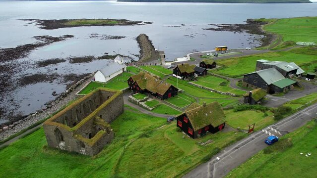 Kirkjubour green village with turf houses and Magnus Cathedral ruins on coast of Streymoy, Faroe