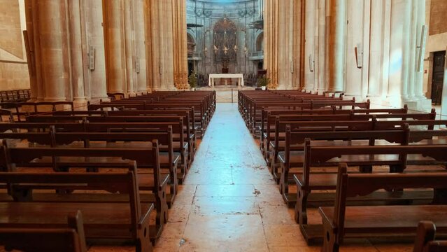 Establishing shot reveals the interior of Lisbon Cathedral, Portugal. Stone columns, arched ceilings and intricate altars fill the space