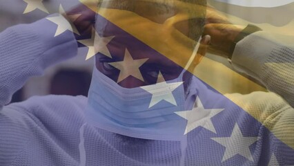 Animation of waving bosnia and herzegovina over african american man wearing face mask on the street - Powered by Adobe