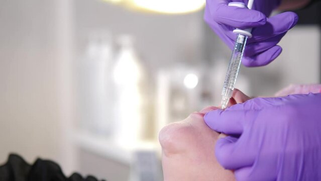 lips augmentation procedure. beauty injections. Vertical footage. Plastic surgery. Hands of cosmetologist making injection to female lips. Woman getting beauty lips correction. Anti-aging treatment