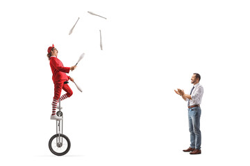 Man giving applause to an acrobat riding a giraffe unicycle and juggling