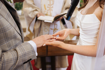 Wedding ceremony background. Catholic church ceremony. Vow moment. Bride putting ring on groom...