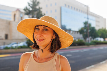 Young beautiful woman walks through the streets on a sunny summer day. Portrait of a girl in a hat.
