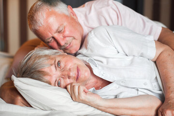 Happy elderly couple wakes up in bed in the morning