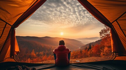 Traveler holding relaxing inside a orange tent and enjoy the view of sunset on autumn forest in national park Generative ai