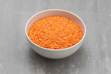 uncooked Red lentils in white bowl on ceramic