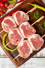 Lamb tenderloin skewer on wood background. Raw lamb tenderloin beyti skewer with herbs and spices. Top view