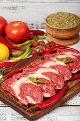 Veal entrecote meat on wood background. Raw beef rib eye steak with herbs and spices