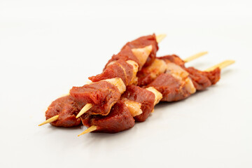 Beef tenderloin skewer isolated on white background. Beef tenderloin skewer with raw sauce with herbs and spices. Close up