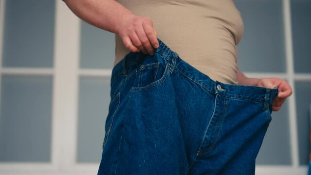 Man trying on extra large jeans, weight loss result, healthy dieting and sports