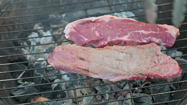 Man cooking and rotating beaf steakes on grill. 4k video footage