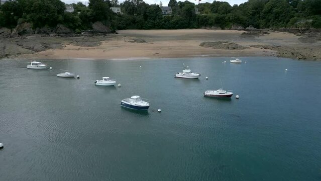 Drone flying over boats moored on Dinard beach in France, Rance dam. Aerial forward