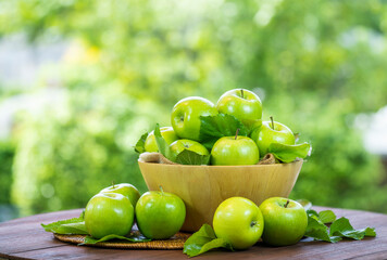 Green Apple on wooden basket, Green Apples with leaf on green bokeh background.