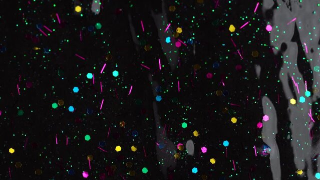 Colorful glitter sparkle confetti background liquid drops of paint color flow down on black canvas. Dark multicolored glitter paint dripping on the black wall. Festive party background