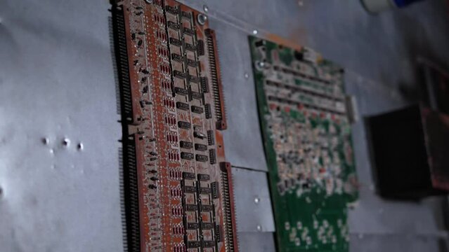 Close-up of broken old microchips with torn wires on the wall of an abandoned factory or production. A dark room with various chips and microchips.