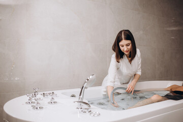Cosmetologist covers the girl with a special blanket in the hydromassage bath. The procedure is a...