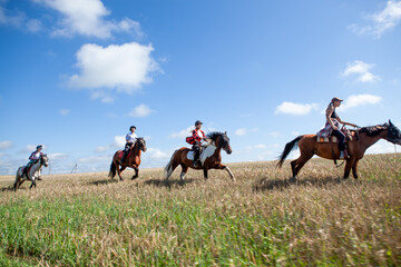 Horseback riding. Horseback riding. Young women equestrians gallop on horses through a field on a...