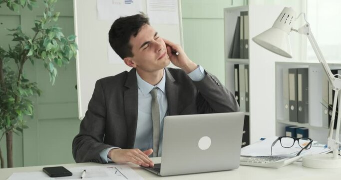 Businessman listening to music and playfully envisioning himself as a desk DJ while seated at his work desk. With playful expression, he taps his fingers and nods his head to the beat.