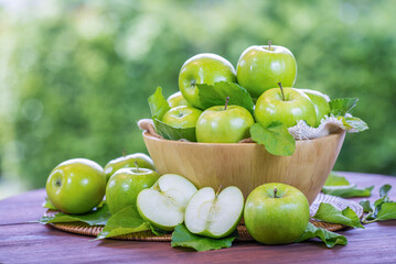 Green Apple on wooden basket, Green Apples and sliced apple with leaf on green bokeh background.