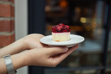 Woman holding birthday berry organic healthy vegetarian  cake against blurred background, closeup. Space for text. High quality photo
