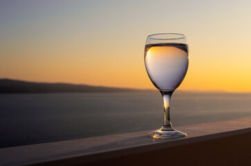 A glass with a drink on the background of the sunset. Selective focus
