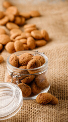 Dutch holiday Sinterklaas traditional cookies kruidnoten in glass jar on sackcloth. Pepernoten, traditional sweets, strooigoed. Concept Saint Nicholas day. Story template and phone background format