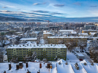 Budynki i bloki mieszkalne miasta Bielsko-Biała w zimie widoczne z lotu ptaka, w tle góry Beskidu i lekko zachmurzone niebo 