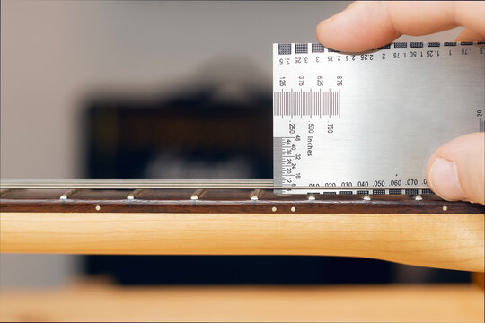 Luthier checks the action on the neck of an electric guitar