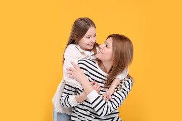 Portrait of happy mother and her cute daughter on orange background