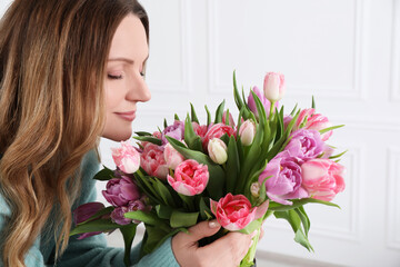 Young woman with bouquet of beautiful tulips indoors