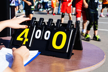 Scoreboard at a street sporting event. The referee turns over the number after a goal is scored in...