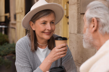 Affectionate senior couple sitting in outdoor cafe and drinking coffee