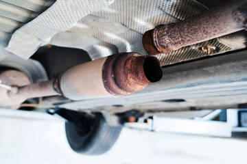 Broken car muffler. Rusty resonator of the sound absorption system. Corrosion of the exhaust pipe...