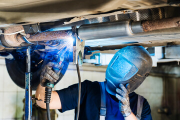 Replacing part of a passenger car exhaust pipe. The welding process and installation of a new resonator or sound absorber. Close-up. Selective focus - obrazy, fototapety, plakaty
