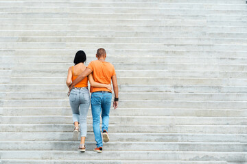 A young couple in an embrace goes up the stairs. A man and a woman in love walk against the...