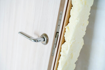A fragment of a dismantled door with dried foam. Unsuccessful installation of an interior door with...