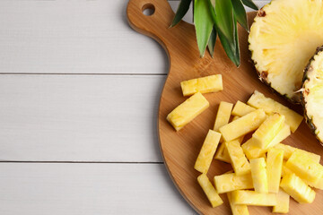 Pieces of tasty ripe pineapple on white wooden table, top view. Space for text