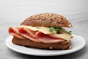 Delicious sandwich with ham and cheese on light gray table, closeup