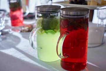 A pair of transparent decanters with berry lemonades of different colors on the festive table. © Татьяна Кутина